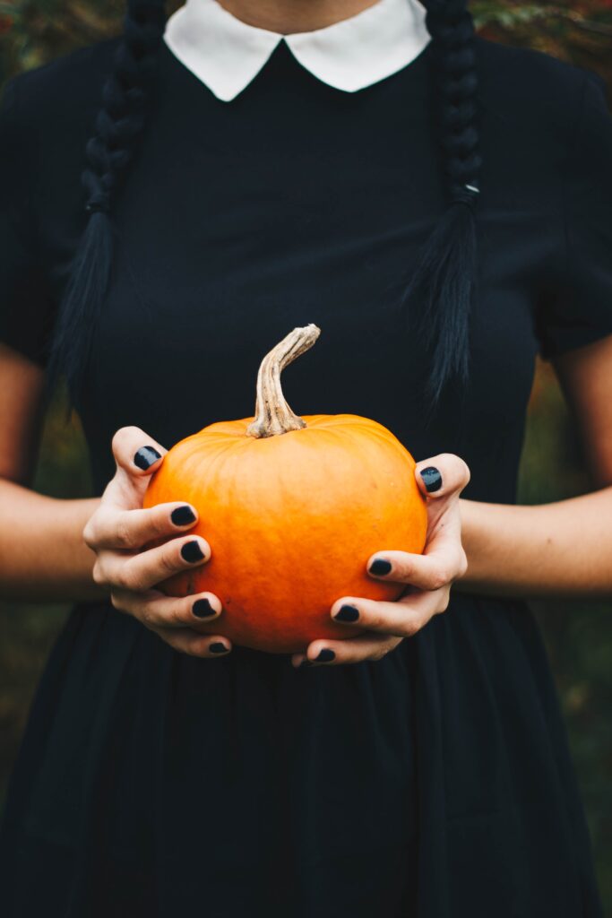 Black dress halloween costume - girl wearing a black dress holding a pumpkin - halloween costume with black dress