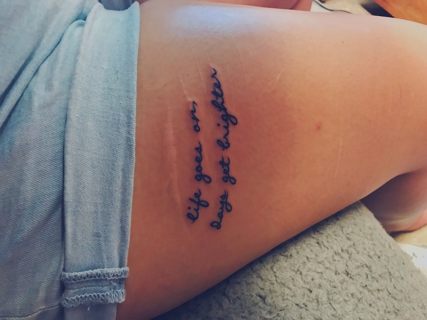 “Life goes on, days get brighter” thigh tattoo