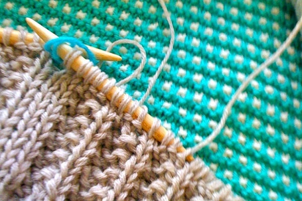 knitting dusty pink yarn on aqua