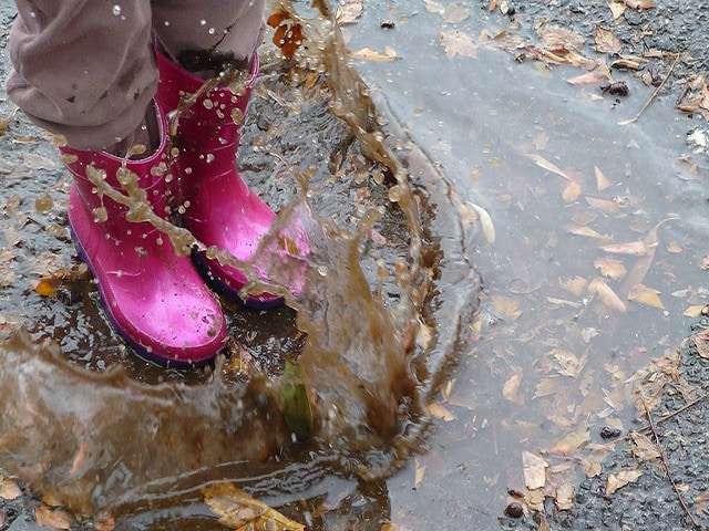 A kid jumping into a puddle