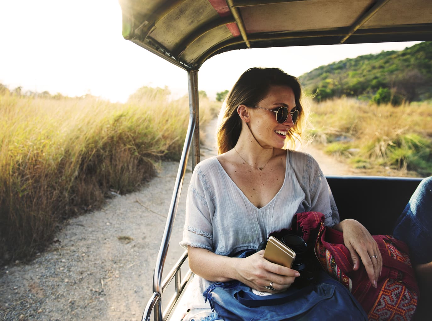 Photo of girl wearing glasses and holding an iPhone in the back of a cart.