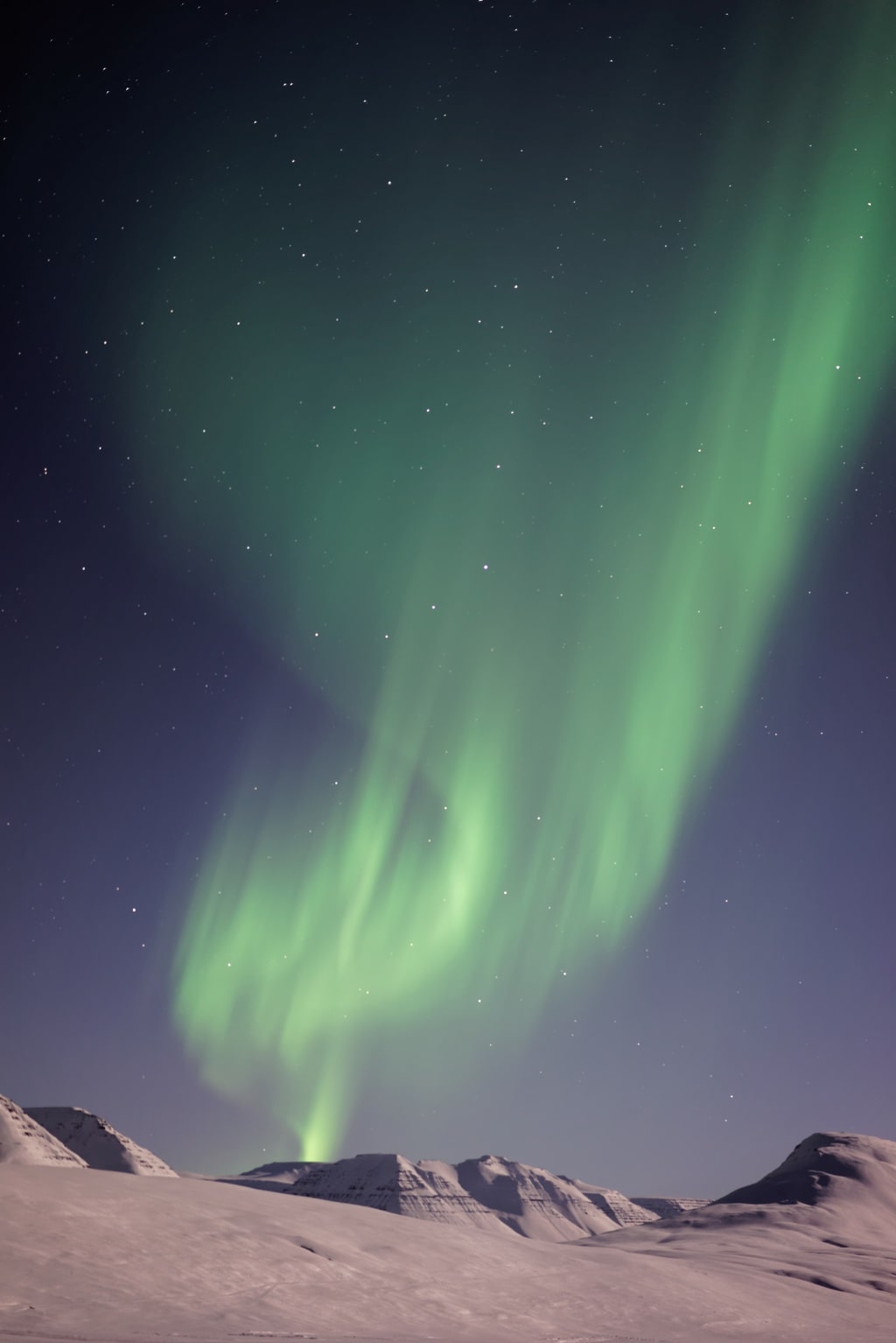 Aurora borealis in the sky over desert mountains