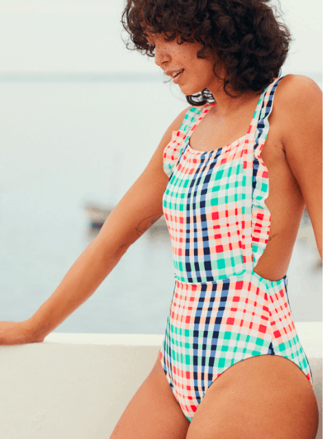 Brunette girl wearing a ruffle one-pice bathing suit with a gingham/checkered pattern on it.