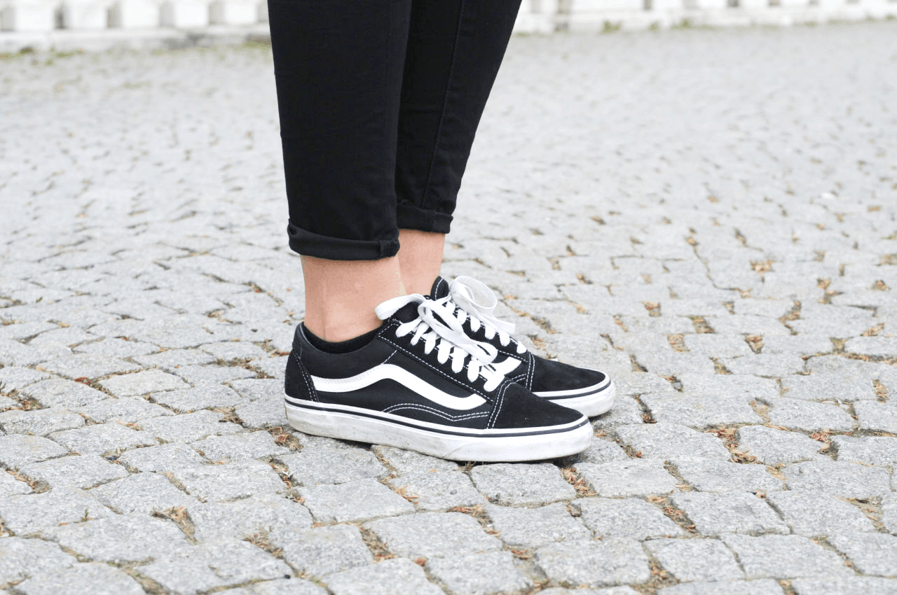 Classic black and white Vans Old Skool sneakers paired with black skinny jeans