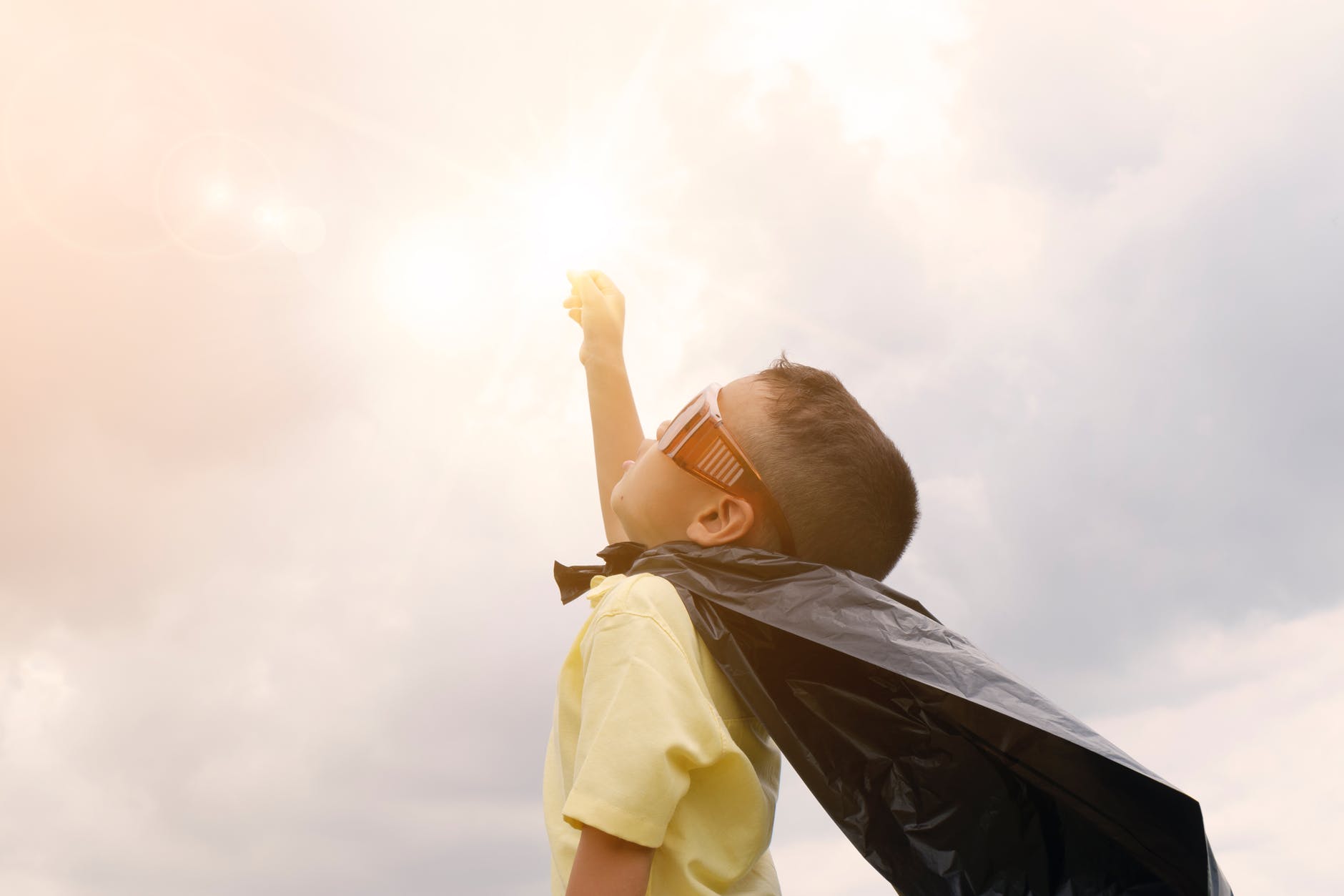 Boy dressed as a superhero with his hand in the air