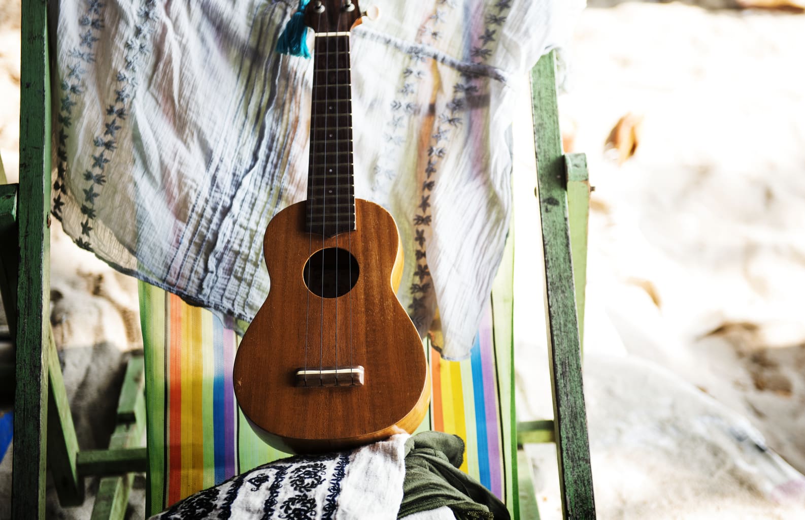 Chill vibes encapsulates this photo with a ukulele chilling on a colorful beach chair.