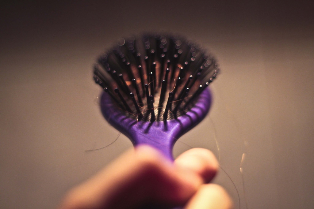 purple hair brush in hand