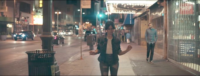 Camila Cabello in her Havana music video dancing in the street wearing jeans and a jean jacket with glasses