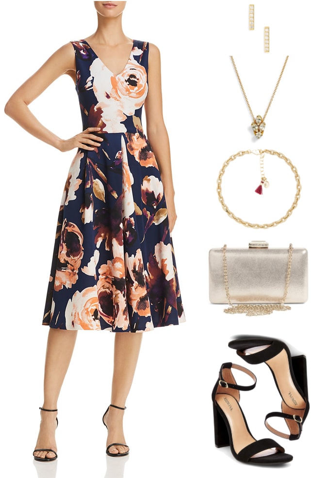 Navy blue sleeveless fit-and-flare midi-length dress with v-neck and large floral print, gold bar stud earrings with clear stones, gold necklace with clear stone pendant, gold bracelet with small pavé clear stone links and light red tassel, pale gold box clutch with chain strap, clasp with clear stones, and gold hardware; black block-heel sandals with ankle strap