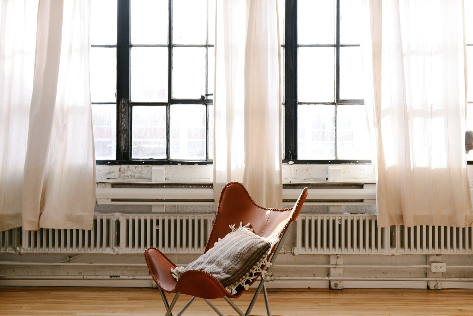 Chair in an apartment with a throw pillow and blanket on it