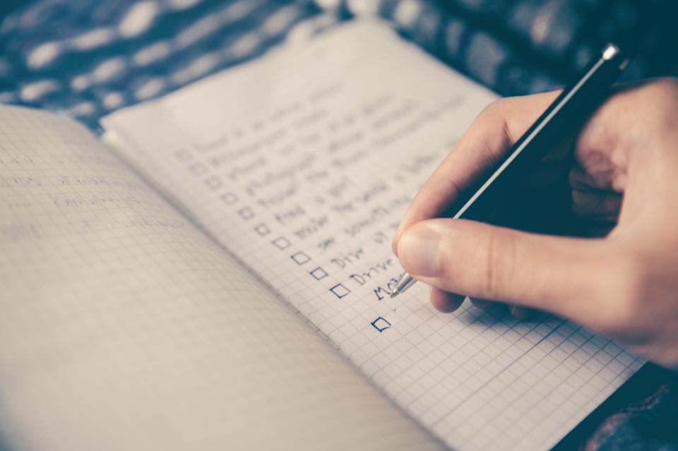 Person writing checklist on grid paper