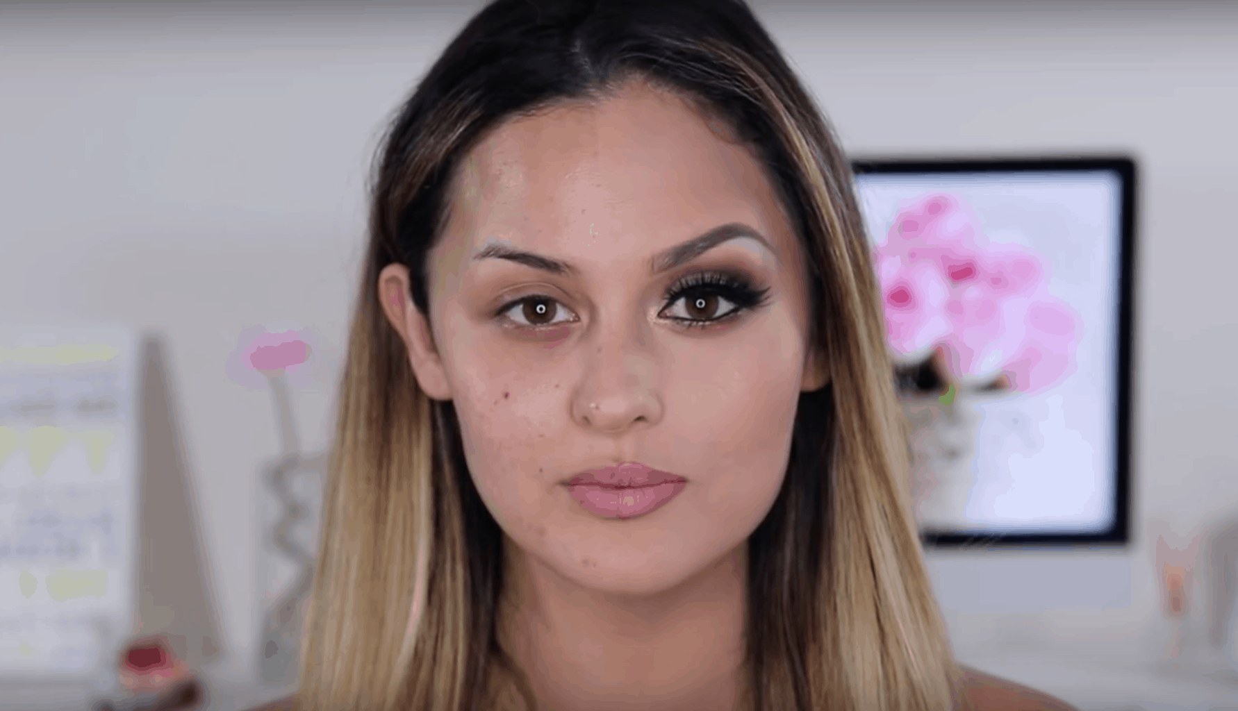 A beauty blogger wearing makeup on half of her face and no makeup on the other half