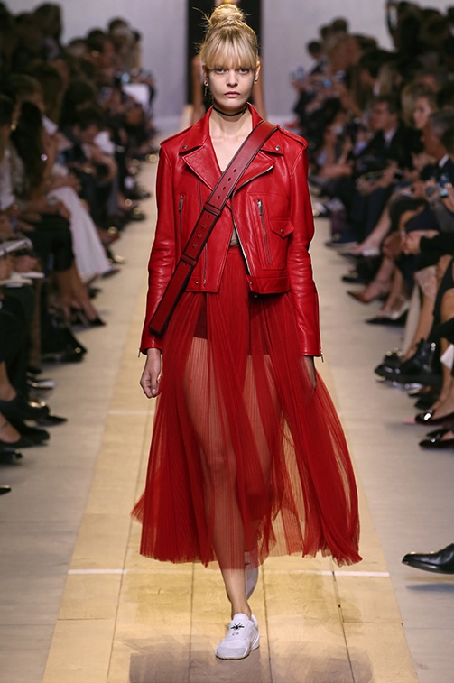 Dior Spring 2017 look 3: Red leather biker jacket worn over a red tulle pleated skirt and white sneakers