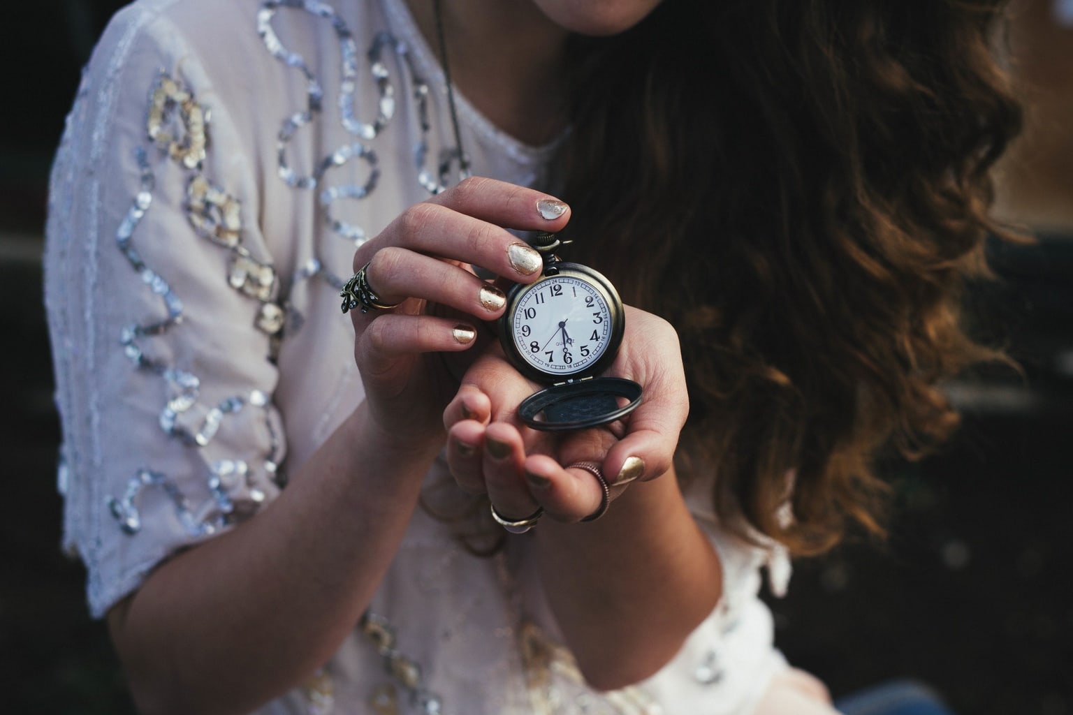 Woman holding a pocket watch with the time 5:30 displayed