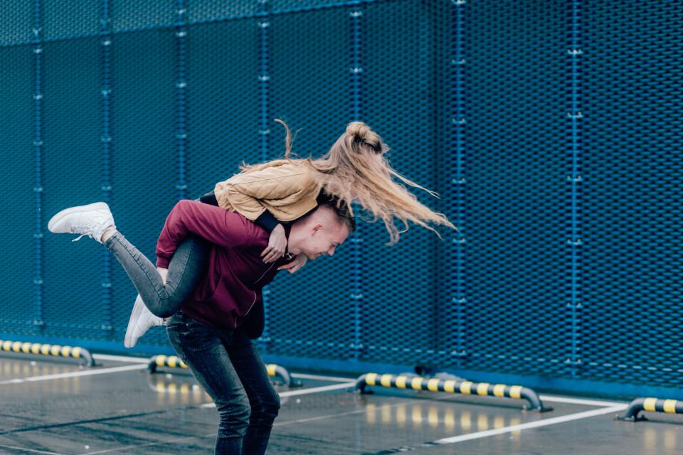 Girl on boy's back having fun in a parking lot