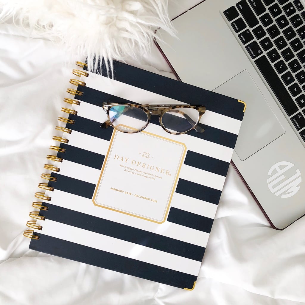 Photo including: a day designer planner, glasses, a furry pillow, and a laptop.