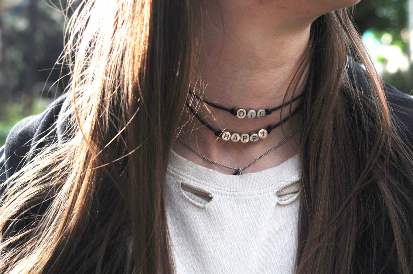 Die Happy choker necklace worn with a ripped white band tee shirt and leather jacket