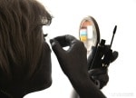Woman doing her makeup in a compact mirror
