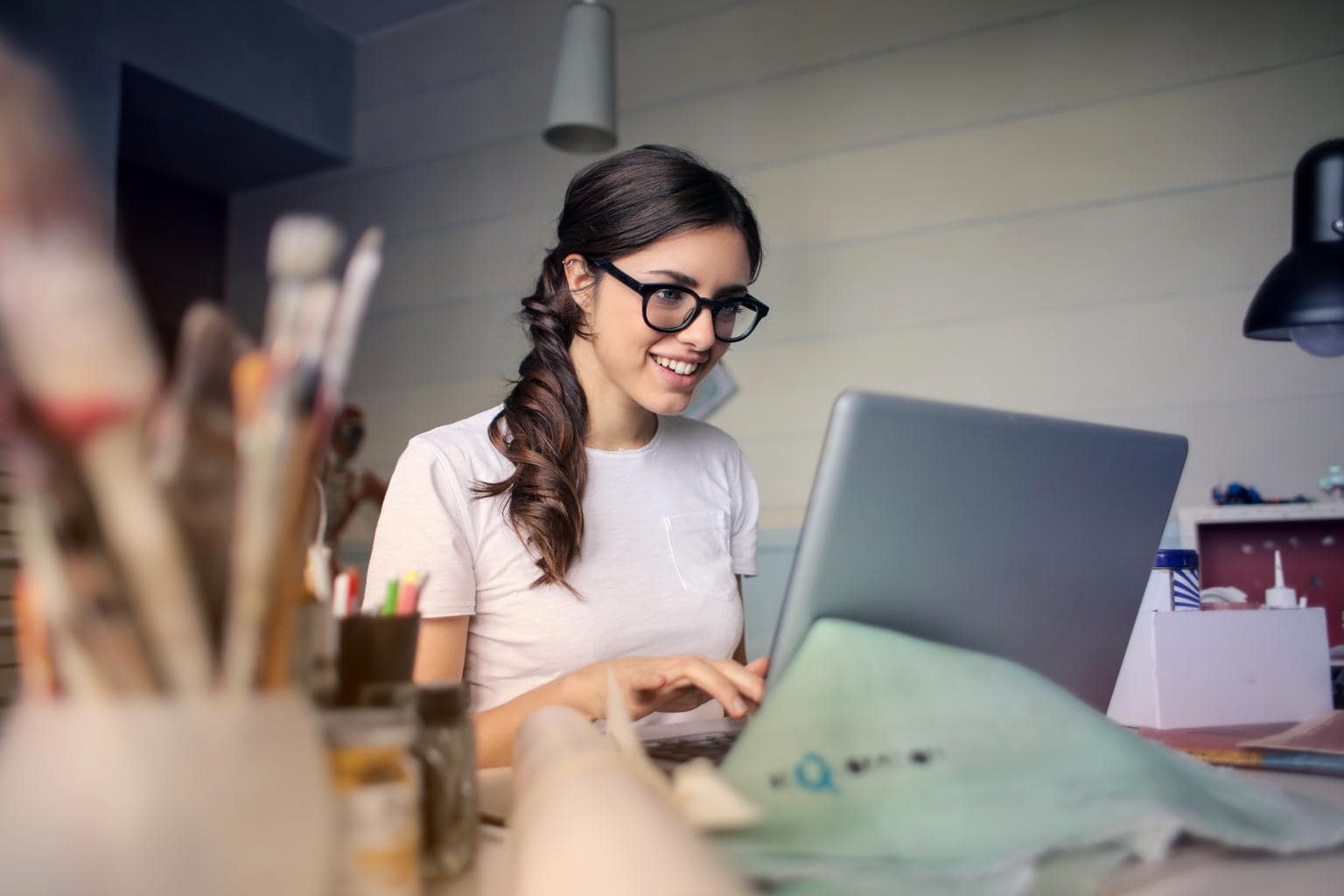 Photo of brunette girl with a ponytail and glasses using a computer.