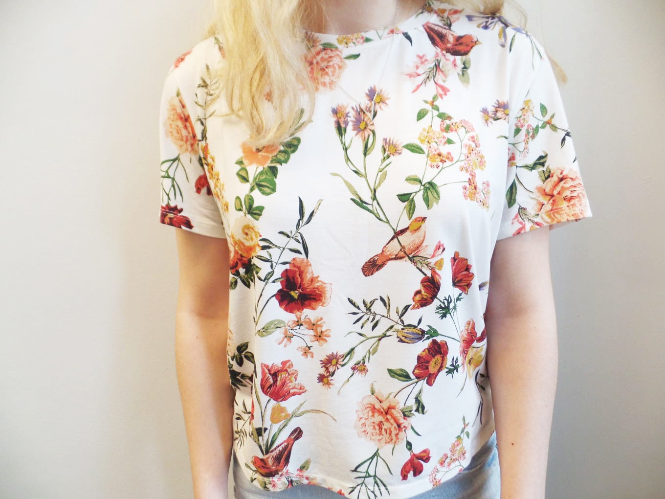 Veronica's short sleeve, crew neck top is covered in a green and orange floral pattern.