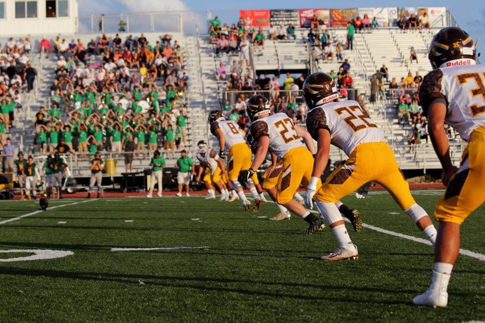 Boys playing football in front of a crowd on bleachers