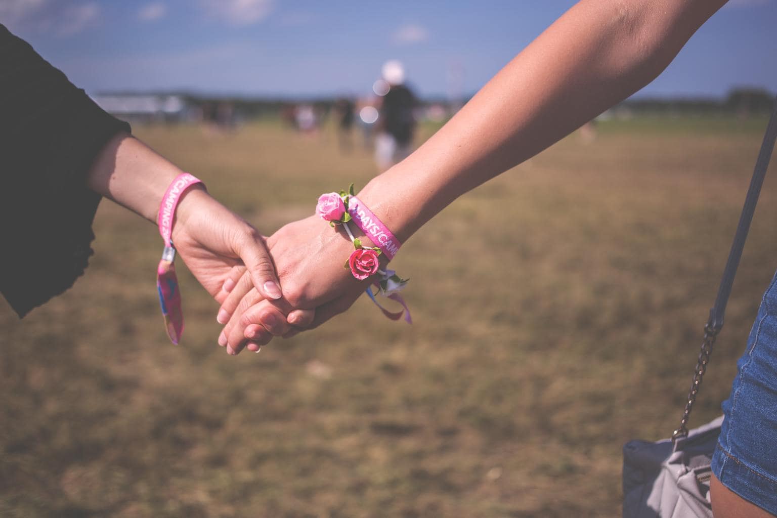 Girls holding hands and wearing friendship bracelets at a music festival