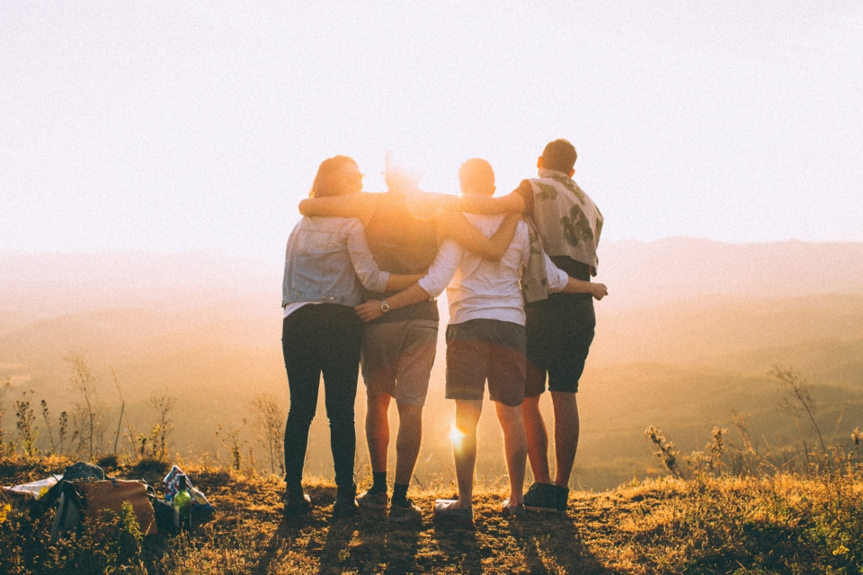 Friends hugging as sun sets on mountain top