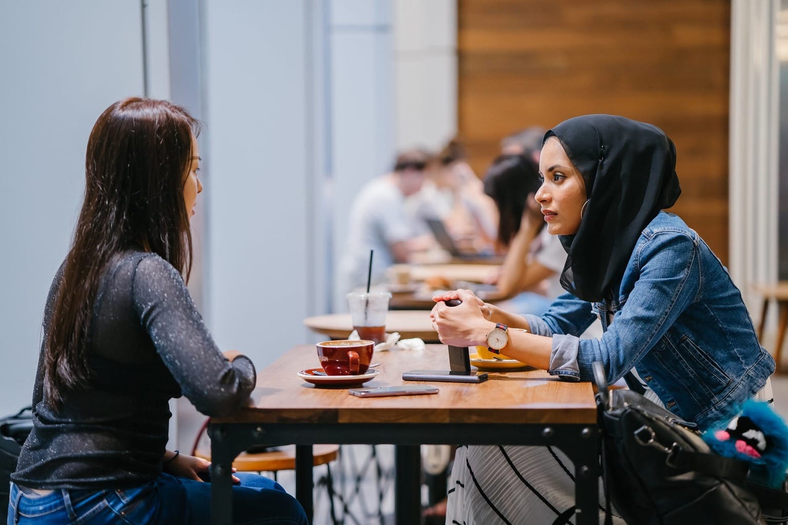 Two friends sitting at a table with coffee talking