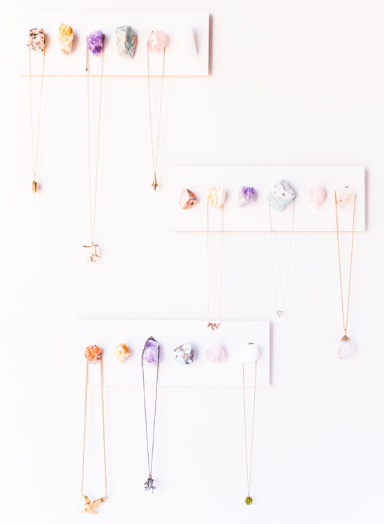 Photo set of three geode/crystal jewelry holders with necklaces hanging off of them.