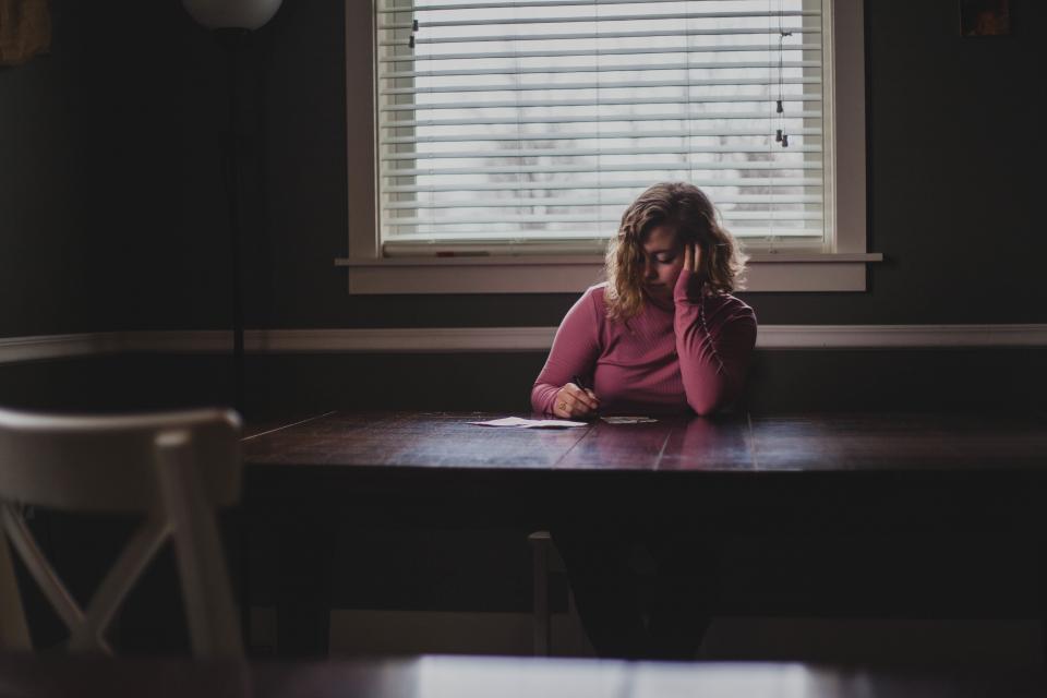 Girl in pink shirt alone at table writing notes