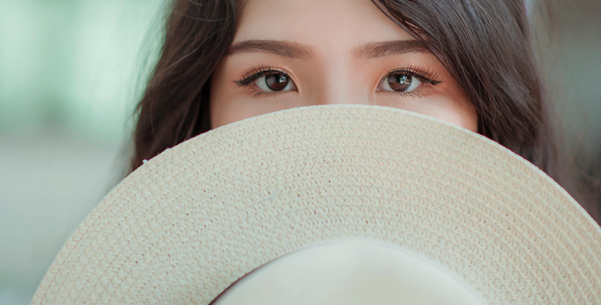 Girl hiding behind a hat