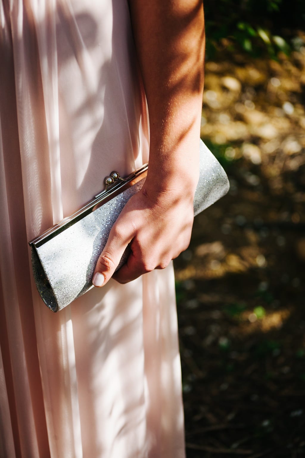 Close-up of a girl in a pale pink gown holding a silver clutch
