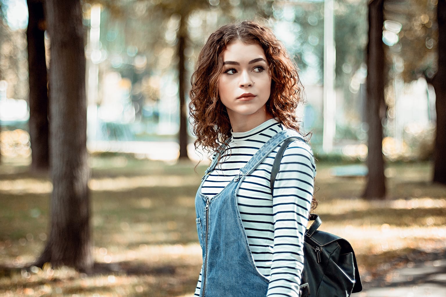 Girl in a striped shirt and overalls taking a walk in the woods