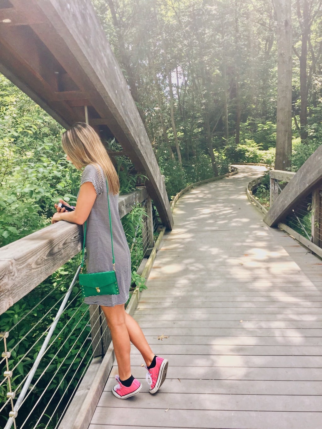 A young girl looks over a bridge at her reflection in the water below