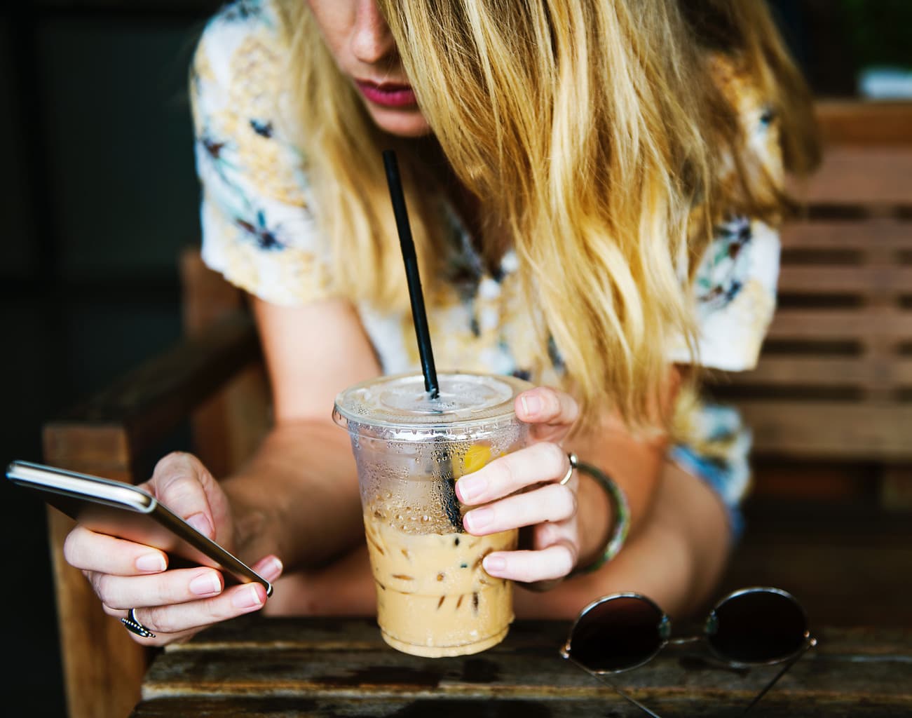Girl using social media on her phone while holding a coffee