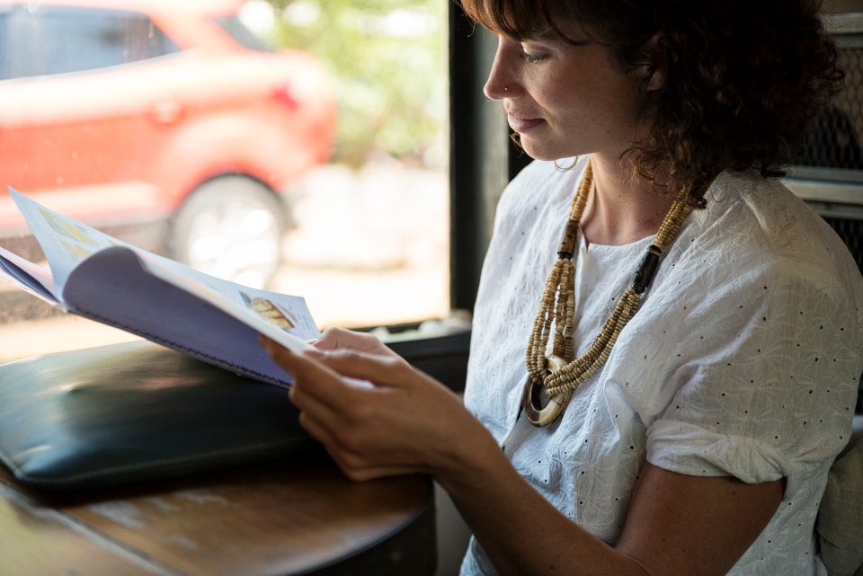 Woman reading in a cafe wearing a white shirt