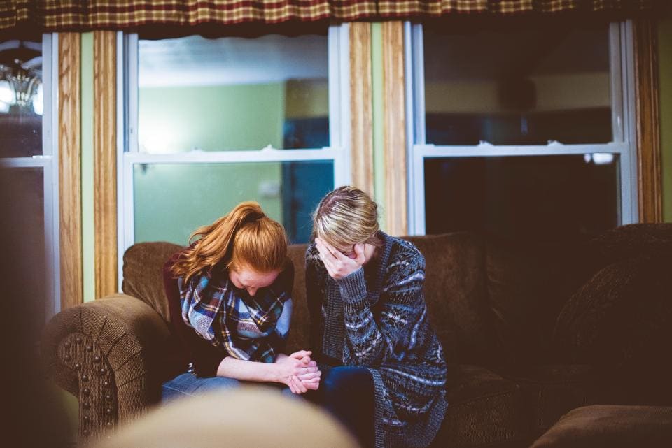 Two girls crying on a couch at night