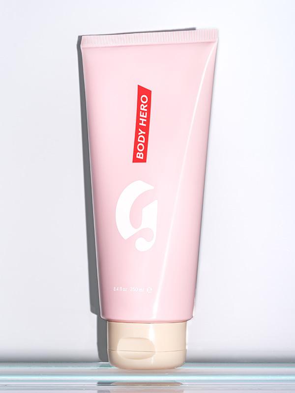 Photo of Glossier Body Hero Daily Perfecting Cream on glass shelf against white background