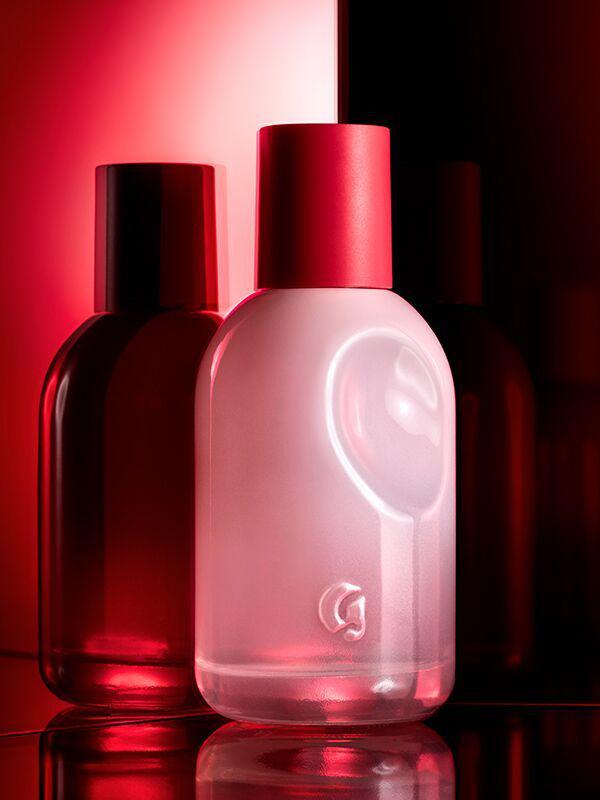 Close-up photo of Glossier You Eau De Parfum Fragrance with shadow against an ombré background that ranges from pale pink to deep red