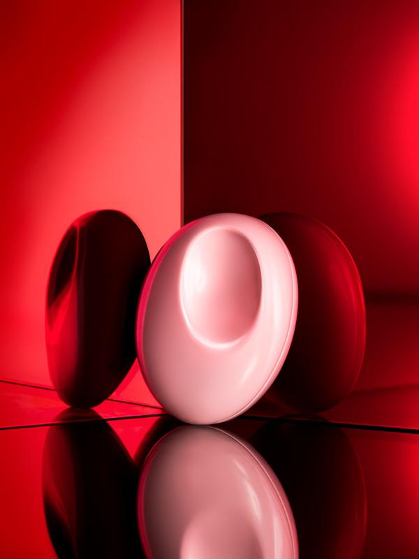 Photo of Glossier You Solid Perfume propped up against a corner that is a reflective and ombré from light to deep red