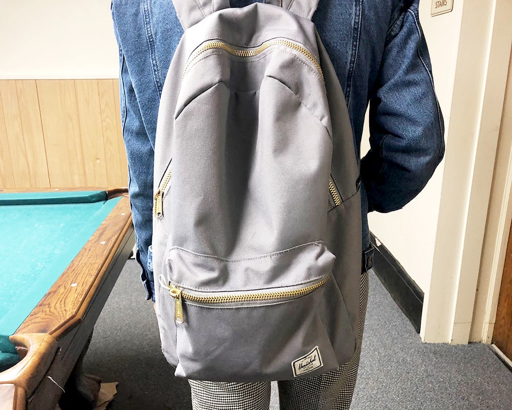 Rachel's grey Hershel Supply Co. backpack has gold accent zippers.