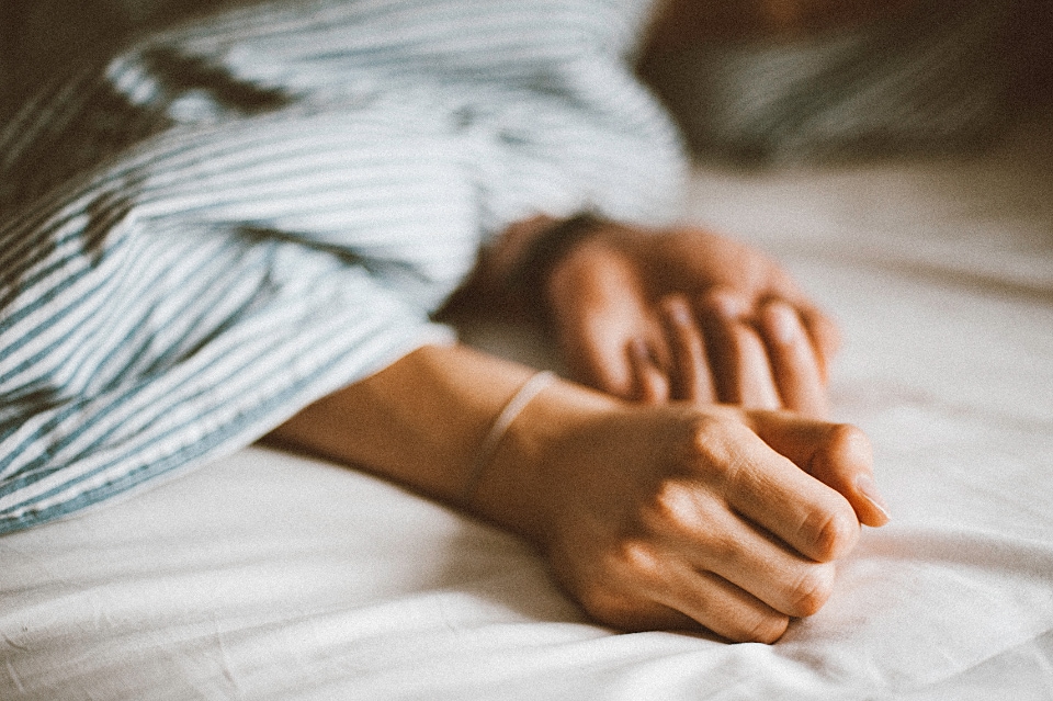 Hands showing in bed under striped comforter