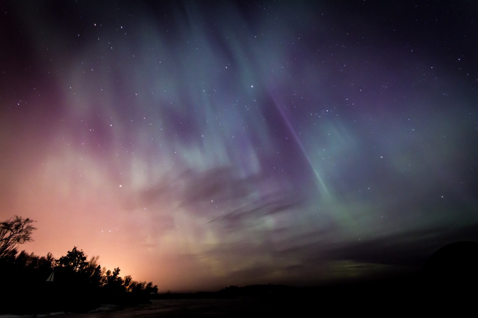 Aurora borealis in the night sky, with the colors pink, green, and purple