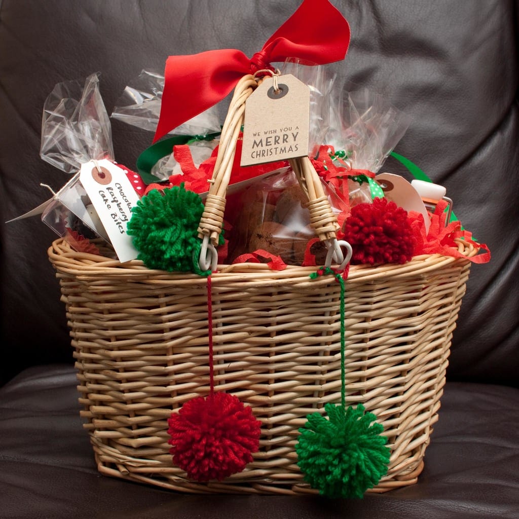 Christmas gift basket with red and green bows and pom poms