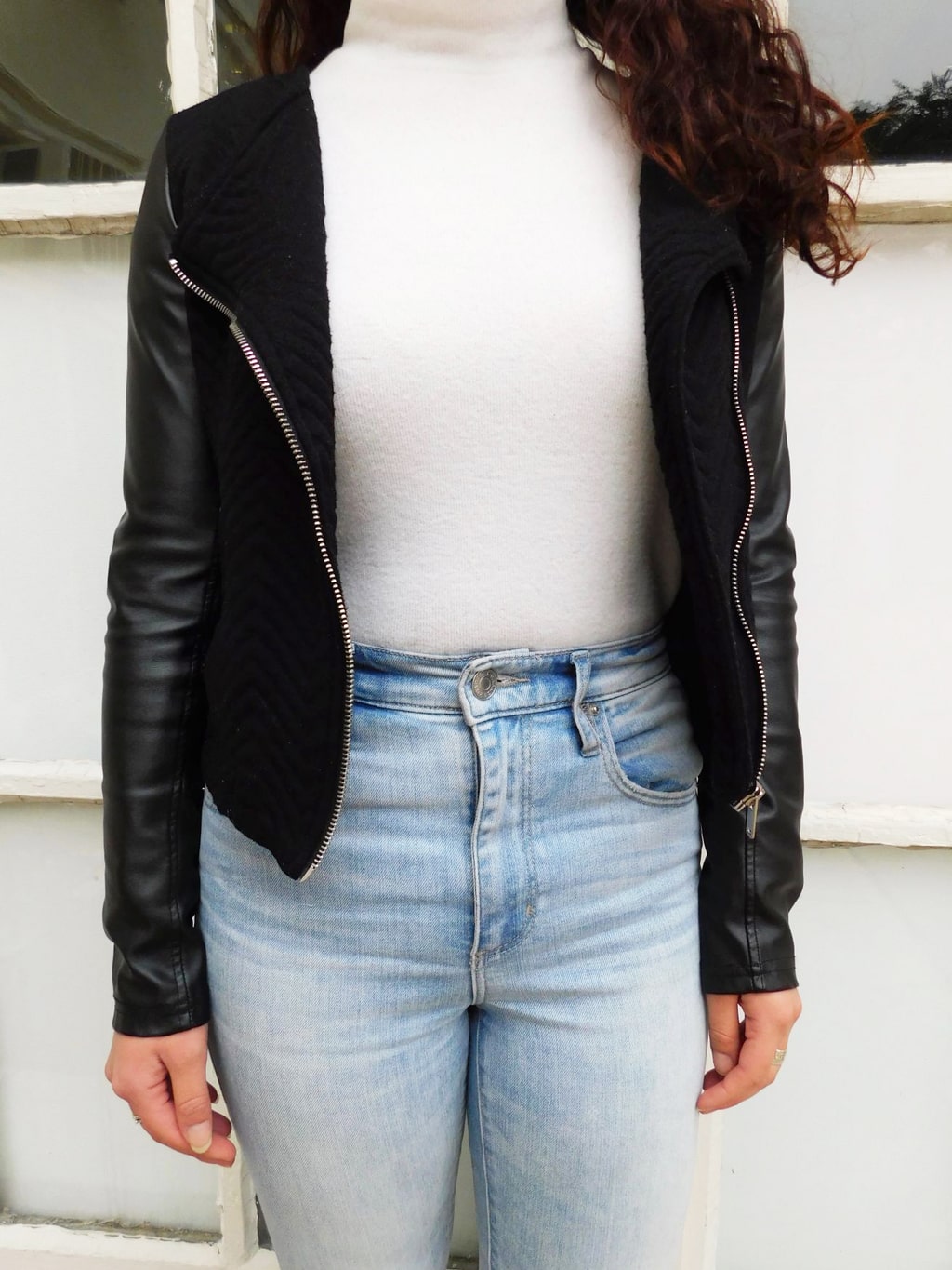 Fashion at Jefferson University: This black motorcycle jacket has is a knit material with faux leather sleeves and silver zippers. It is worn here with a white turtleneck and high-waisted denim jeans.