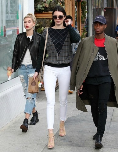 Kendall Jenner wearing a graphic print sweater and white skinnies