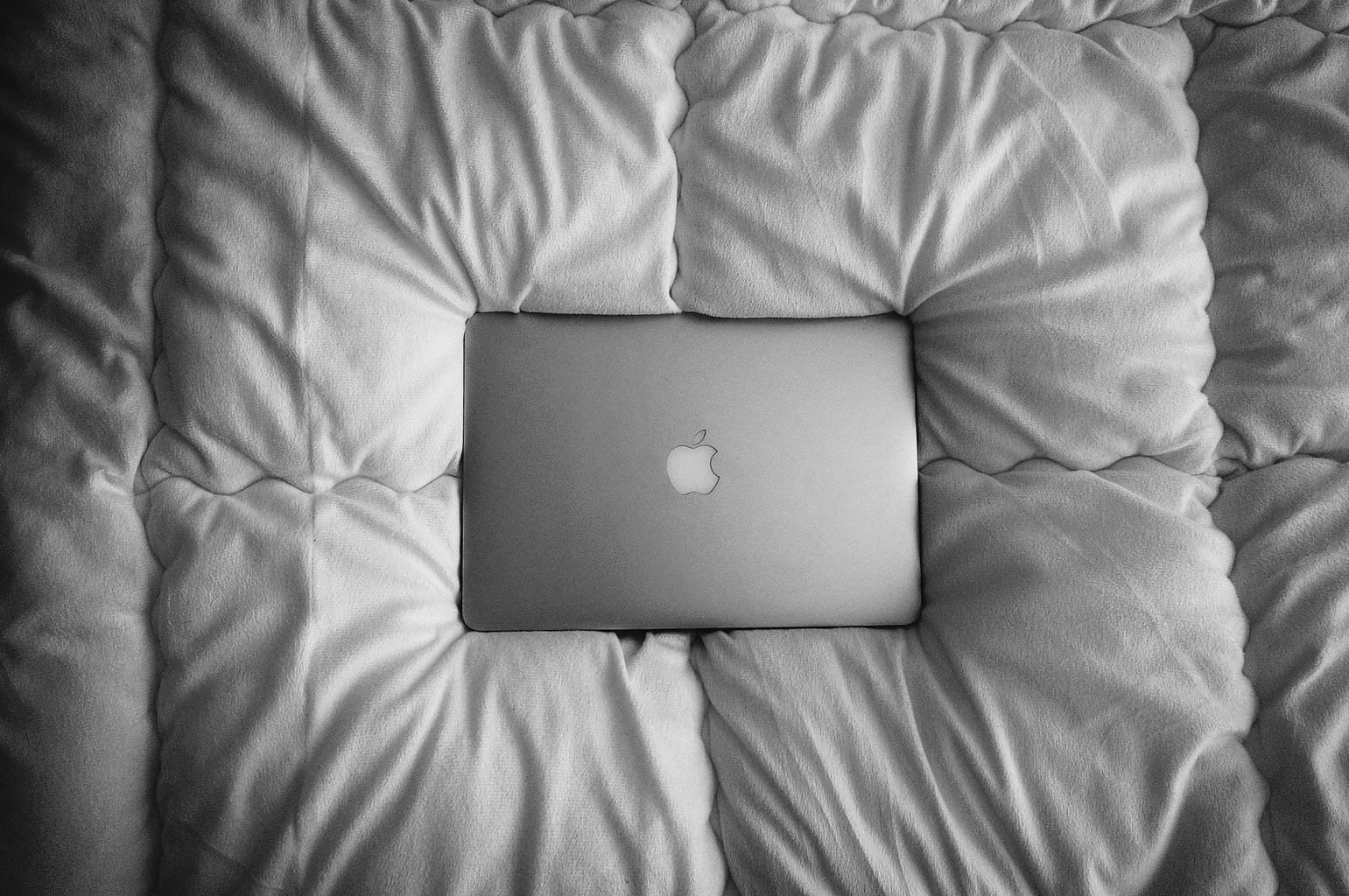 grey laptop on grey bed