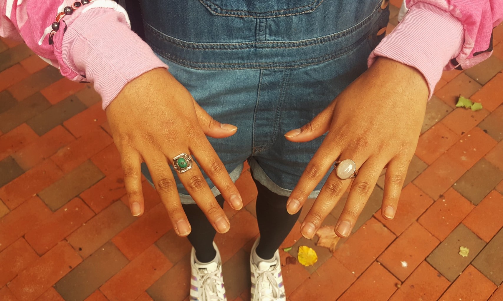 Barnard College student Alema sports mismatched accessories with a pink windbreaker jacket. Her oval opal ring and bright green vintage silver ring compliment her overall shorts.