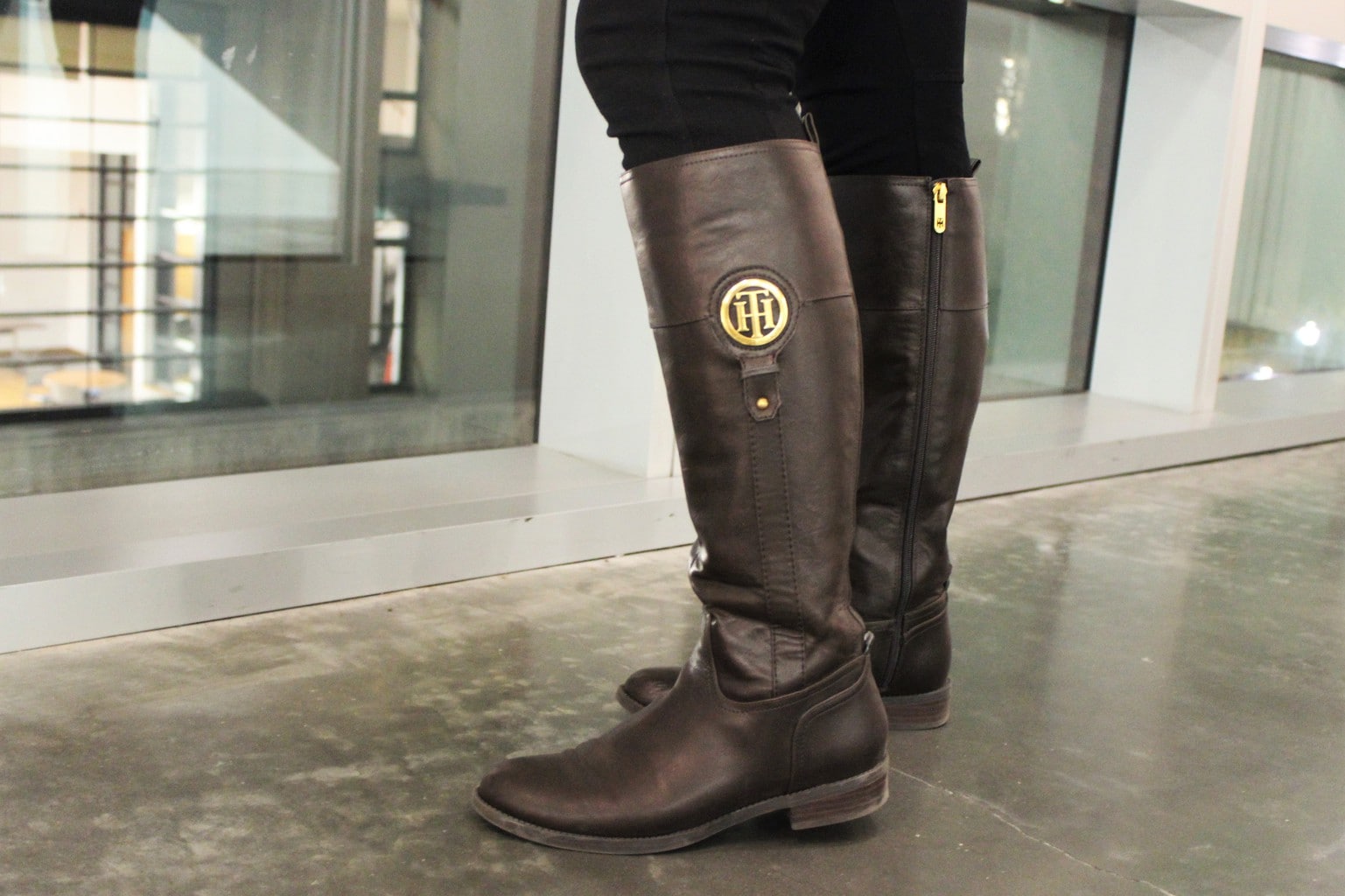 Catherine wears tall flat brown riding boots with gold accents.