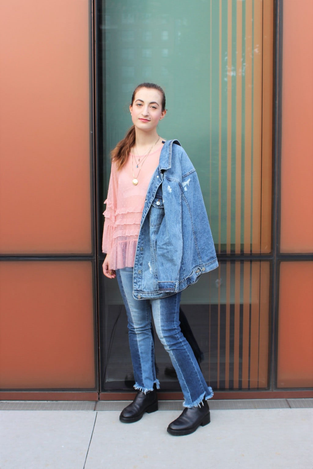 Barnard College at Columbia University student Francesca wears the perfect denim on denim outfit with a ruffled, sheer pink blouse with a white lace bralette underneath, patchwork raw-edge denim jeans, and an oversized light-wash denim jacket.